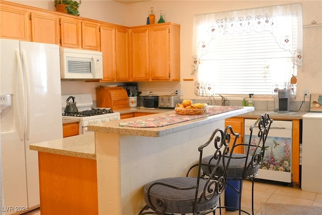 kitchen with white appliances, light tile patterned floors, and a kitchen bar