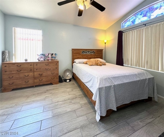 bedroom featuring ceiling fan, light wood-type flooring, and vaulted ceiling