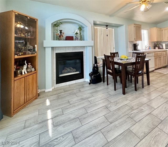 dining space with ceiling fan and a tile fireplace