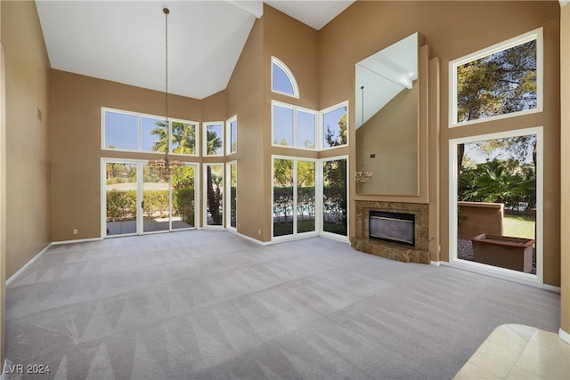 unfurnished living room with light carpet, a towering ceiling, and a wealth of natural light