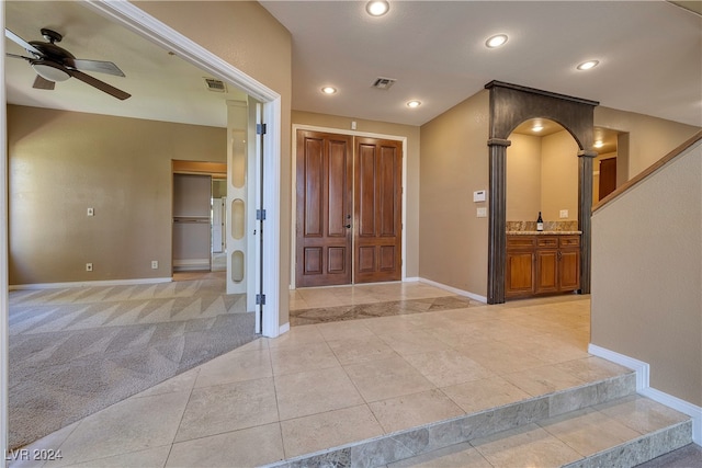 foyer entrance featuring ceiling fan and light colored carpet