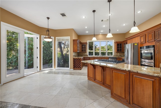 kitchen with pendant lighting, light stone countertops, stainless steel appliances, and light tile patterned flooring