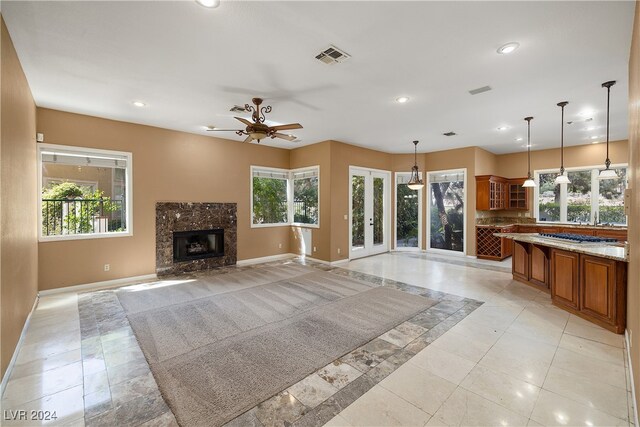 unfurnished living room with light tile patterned floors, a wealth of natural light, a fireplace, and ceiling fan