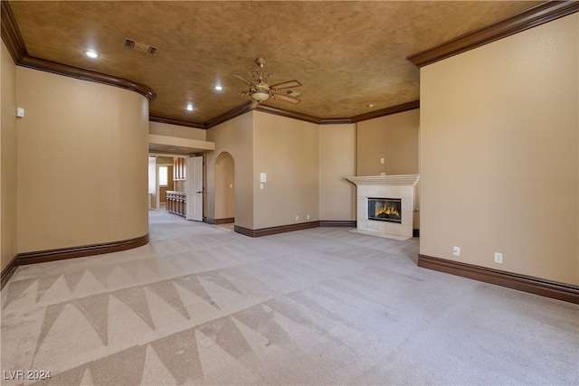 unfurnished living room featuring a tile fireplace, light carpet, ceiling fan, and crown molding