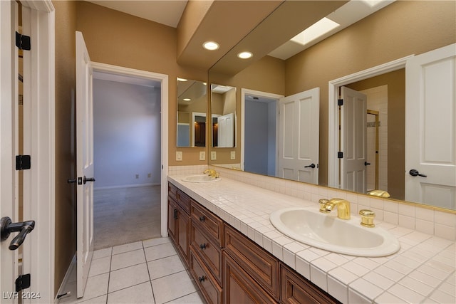 bathroom with tile patterned flooring, vanity, and a skylight