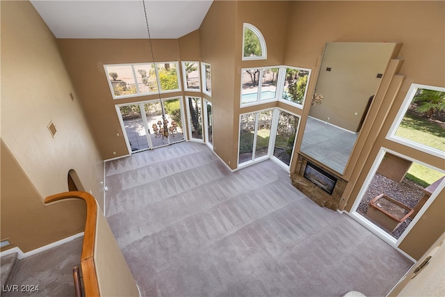 living room featuring an inviting chandelier, light colored carpet, and a high ceiling