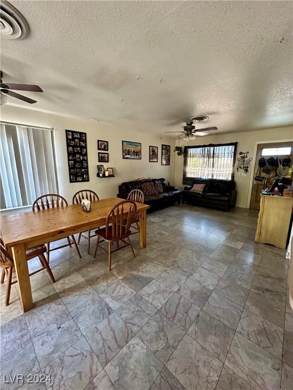 dining space with a textured ceiling and ceiling fan