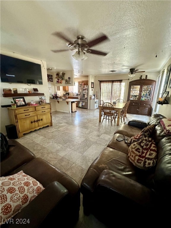 living room with ceiling fan and a textured ceiling