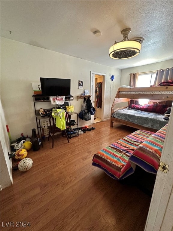 bedroom featuring a textured ceiling, wood-type flooring, a spacious closet, and a closet