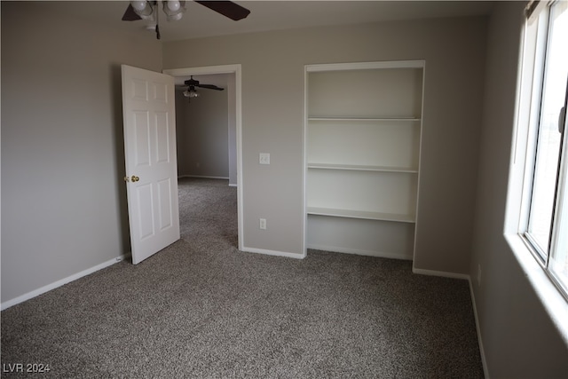 unfurnished bedroom featuring carpet flooring, ceiling fan, multiple windows, and a closet