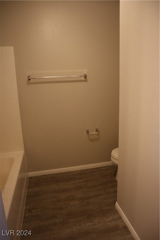 bathroom with a bath, hardwood / wood-style flooring, and toilet