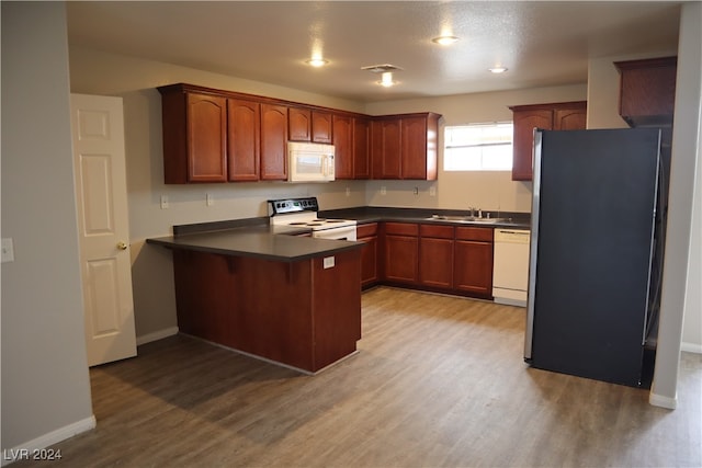 kitchen featuring sink, white appliances, kitchen peninsula, and wood-type flooring