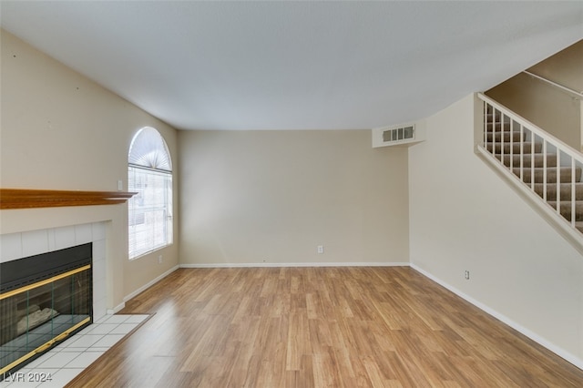 unfurnished living room featuring light hardwood / wood-style flooring and a tile fireplace