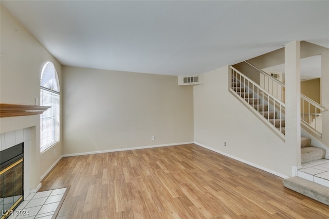 unfurnished living room with light hardwood / wood-style flooring and a tile fireplace