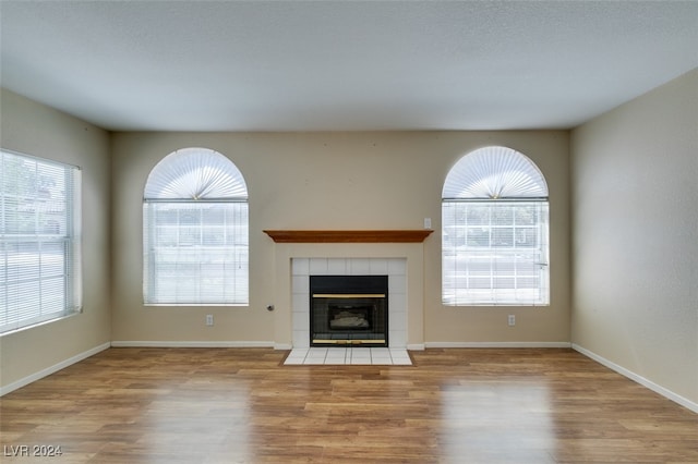 unfurnished living room featuring light wood-type flooring, a fireplace, and a wealth of natural light