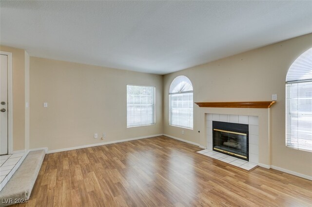 unfurnished living room featuring light hardwood / wood-style flooring and a tile fireplace