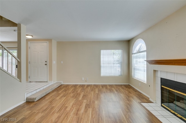 unfurnished living room featuring a tiled fireplace and light hardwood / wood-style flooring