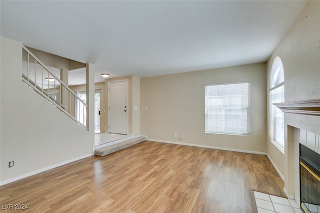 unfurnished living room featuring light wood-type flooring and a tiled fireplace