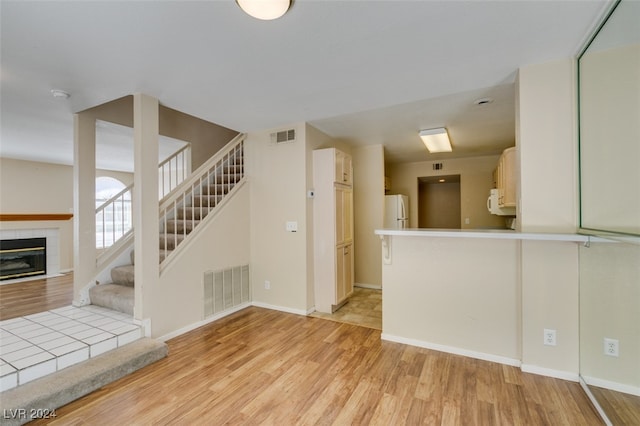 unfurnished living room with light hardwood / wood-style flooring and a tiled fireplace