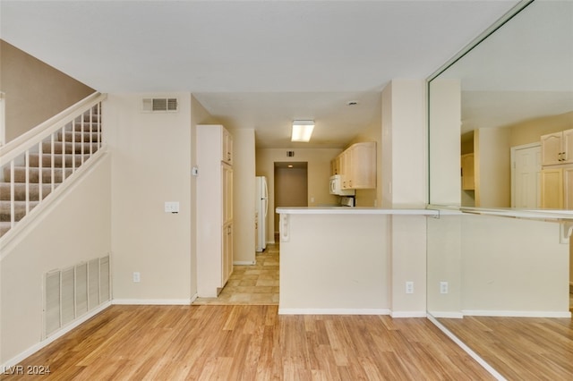 interior space with kitchen peninsula, white appliances, and light hardwood / wood-style floors