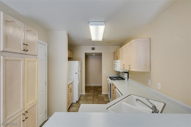 kitchen with sink, light tile patterned floors, and white appliances