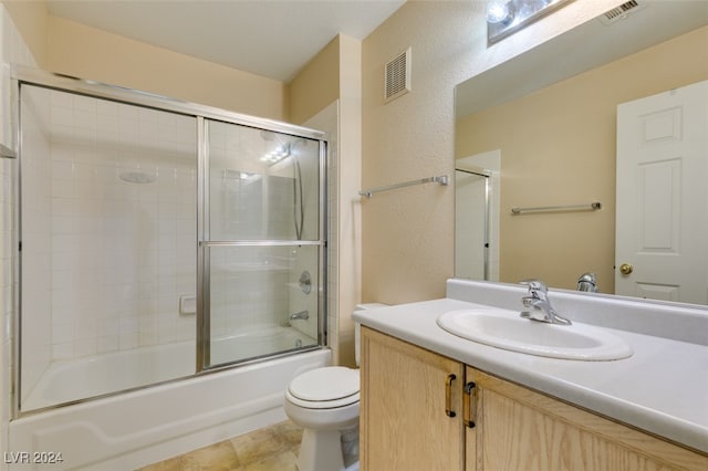 full bathroom featuring shower / bath combination with glass door, tile patterned flooring, toilet, and vanity