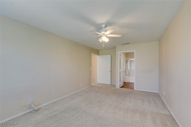 unfurnished bedroom with ceiling fan, light colored carpet, and ensuite bathroom