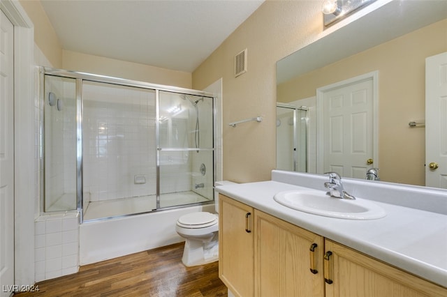 full bathroom featuring shower / bath combination with glass door, vanity, toilet, and hardwood / wood-style floors