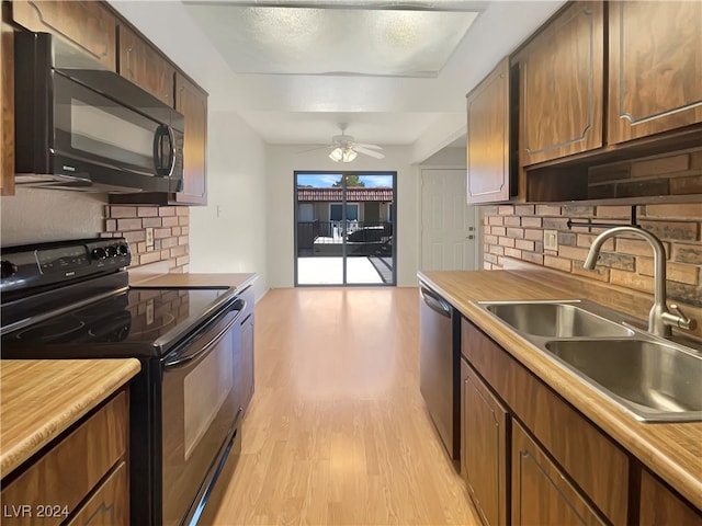 kitchen with backsplash, light wood-type flooring, sink, black appliances, and ceiling fan