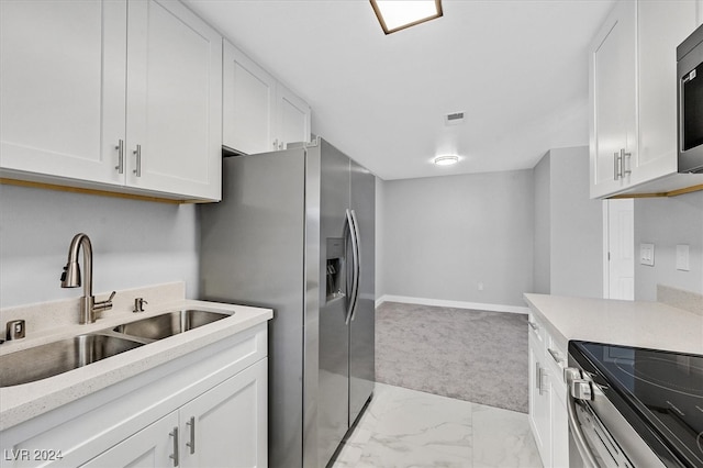 kitchen featuring sink, light carpet, and white cabinets