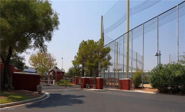 view of street featuring a gate, a gated entry, and curbs