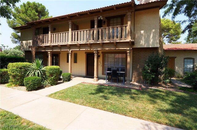 exterior space featuring a front lawn and a balcony