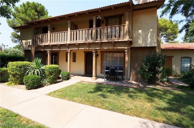 mediterranean / spanish-style house featuring a balcony, a front lawn, and stucco siding