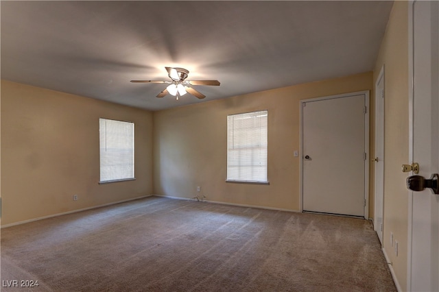 spare room with carpet, a ceiling fan, and baseboards