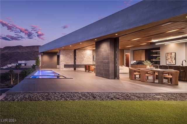 back house at dusk featuring a yard, a patio, and a mountain view