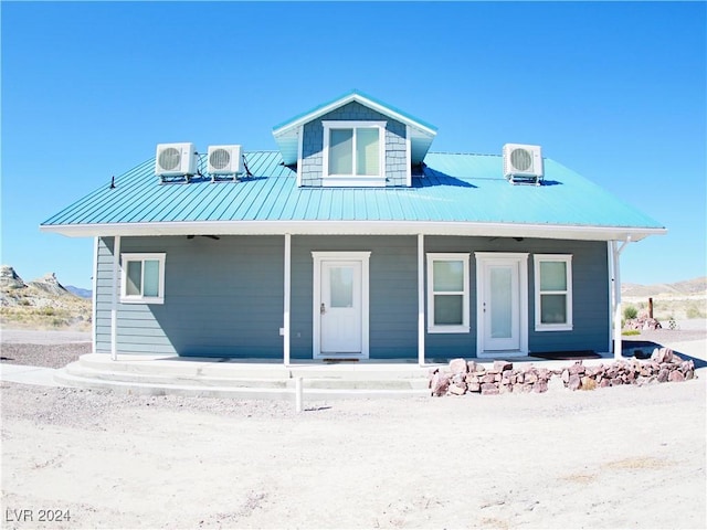 view of front of home featuring ac unit, covered porch, cooling unit, metal roof, and a standing seam roof