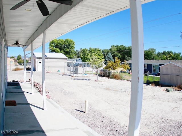 view of patio / terrace with an outdoor structure, a ceiling fan, fence, and a shed