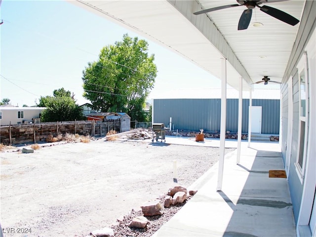 view of patio featuring an outdoor structure, a ceiling fan, and fence