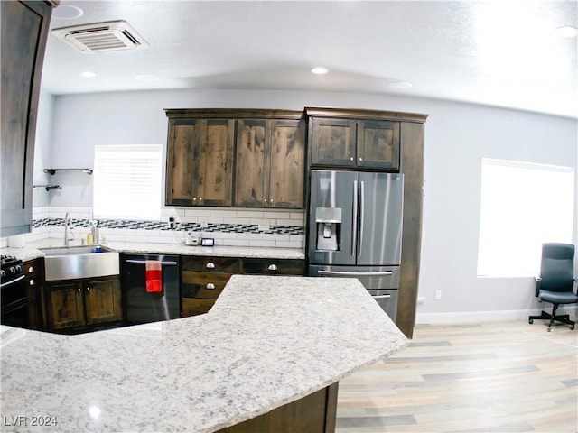 kitchen with visible vents, dark brown cabinetry, dishwashing machine, stainless steel refrigerator with ice dispenser, and a sink