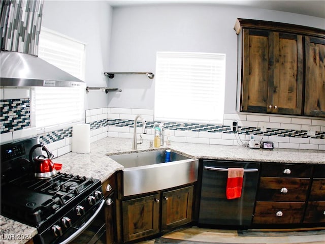 kitchen with gas stove, a sink, dark brown cabinets, dishwasher, and wall chimney range hood