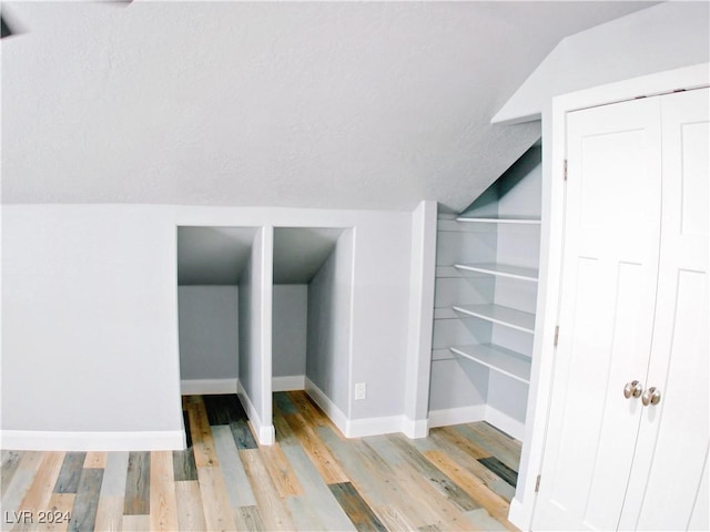 interior space featuring vaulted ceiling, baseboards, and light wood finished floors