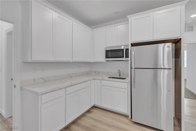 kitchen with fridge, light hardwood / wood-style floors, white cabinetry, and sink