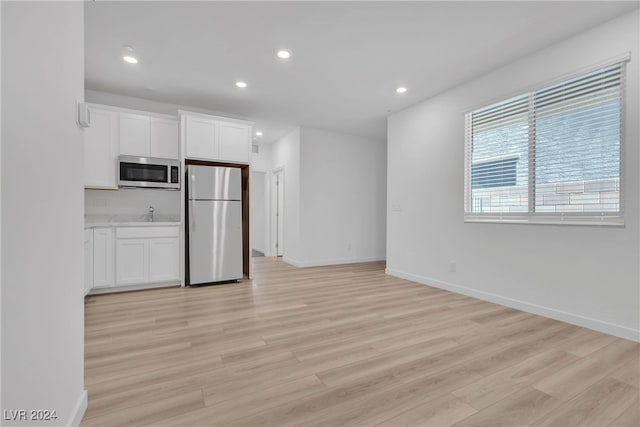 interior space with fridge, white cabinets, and light hardwood / wood-style floors