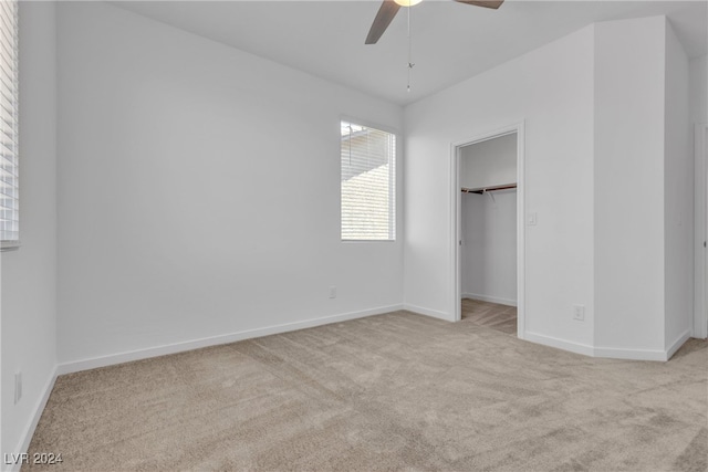 unfurnished bedroom featuring ceiling fan, light colored carpet, a closet, and a walk in closet