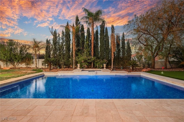 pool at dusk featuring a patio area, a fenced backyard, and an outdoor pool