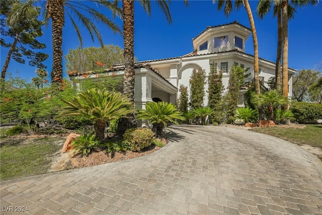 view of front of house featuring decorative driveway, a tile roof, and stucco siding