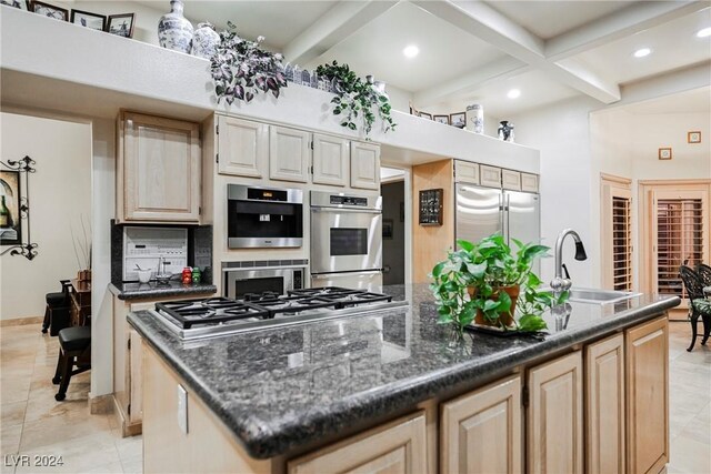 kitchen with a center island with sink, sink, light tile patterned floors, and backsplash