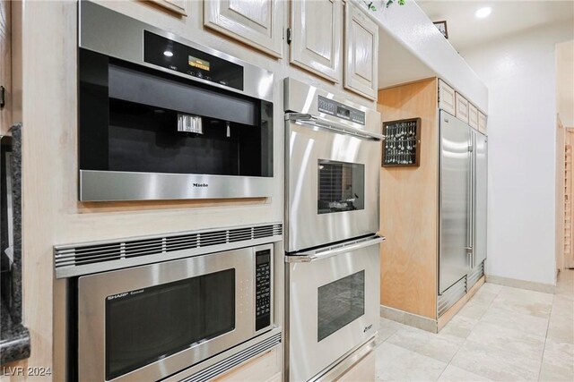 kitchen featuring built in appliances and light tile patterned flooring