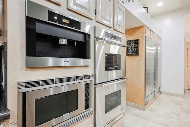 kitchen featuring light tile patterned floors, baseboards, and built in appliances