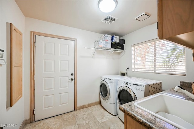 washroom featuring washing machine and dryer, a sink, visible vents, baseboards, and cabinet space